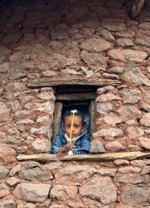 Child peers through Tukul window 
