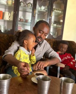 Berhe enjoys a coffee while sitting with his children